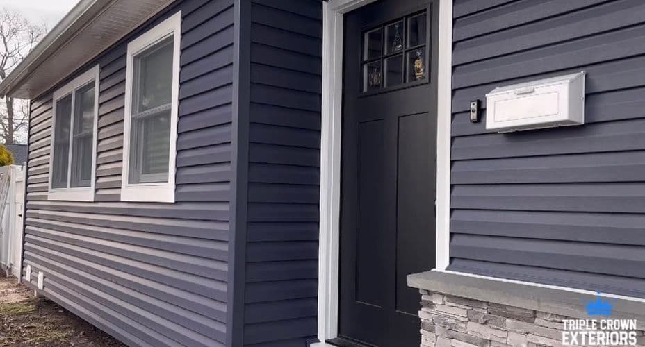 Modern home exterior with dark siding, stylish entrance door, and stone accents.