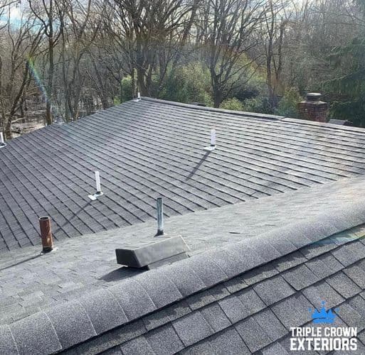 Newly installed gray asphalt shingle roof with ventilation pipes, showcasing quality craftsmanship.