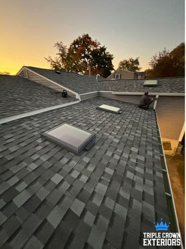 Roof installation at sunset featuring skylights by Triple Crown Exteriors.