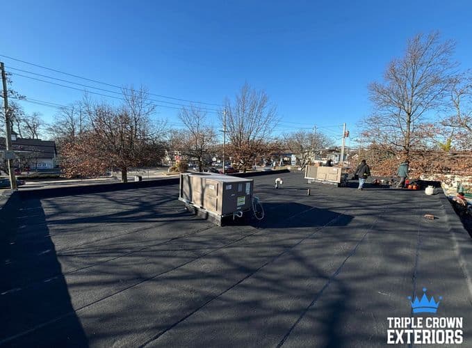 Newly installed flat roof with HVAC units in a residential neighborhood on a clear day.