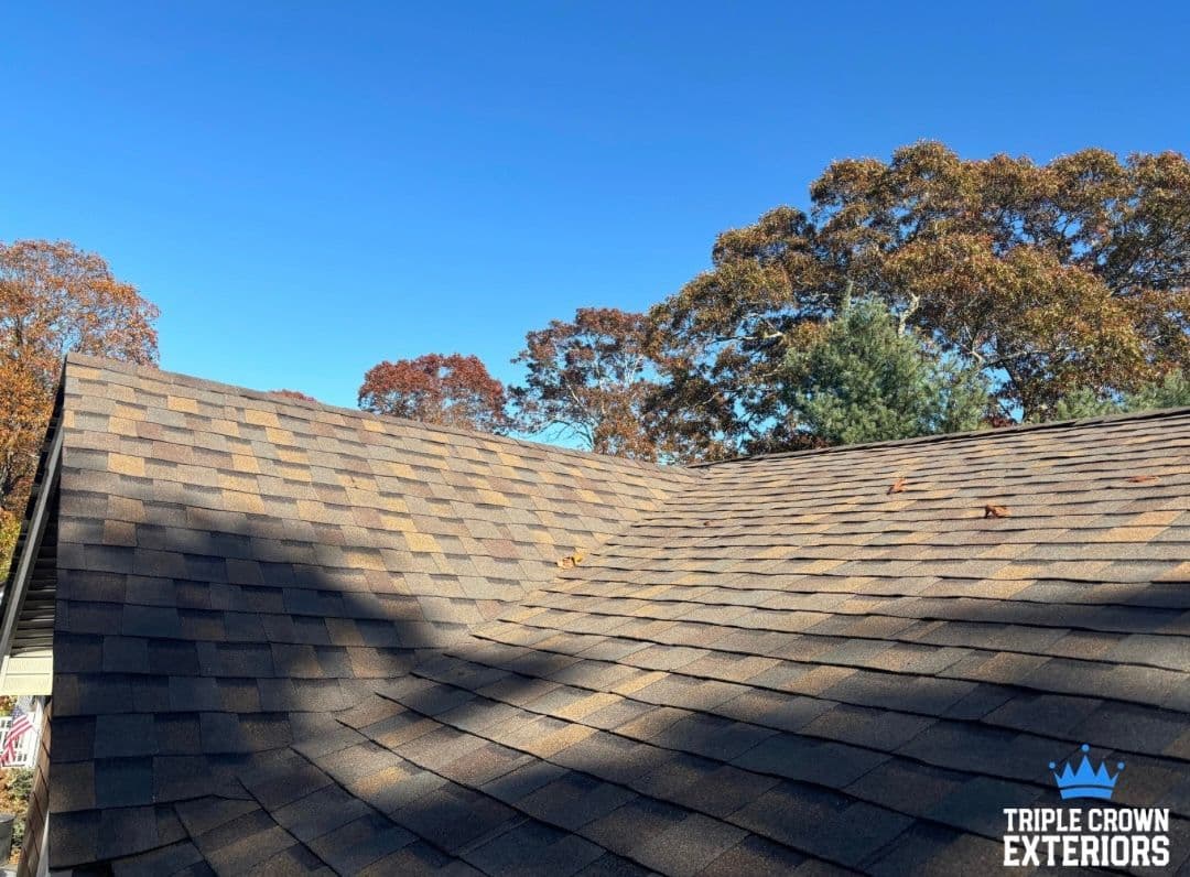 Roofing project showcasing a newly installed shingle roof under a clear blue sky.