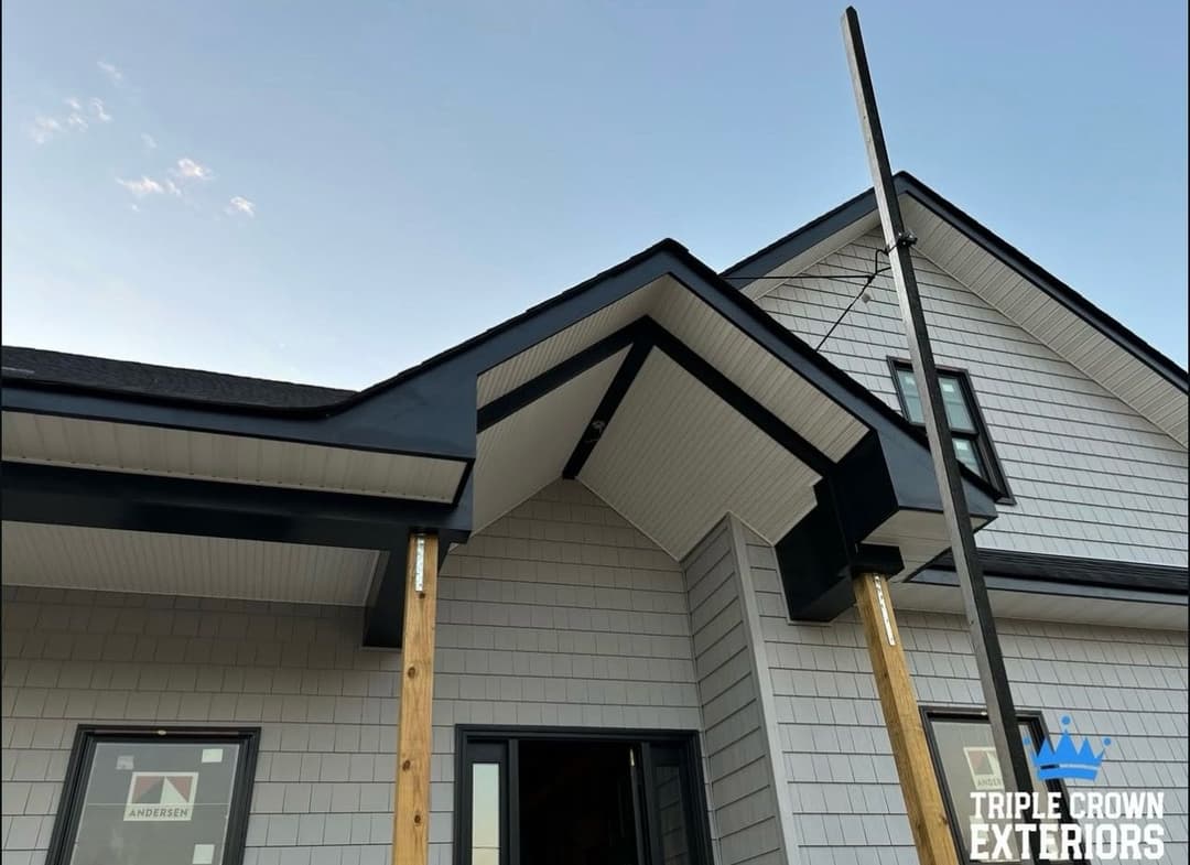 Modern home exterior with black trim, showcasing architectural details and construction work.