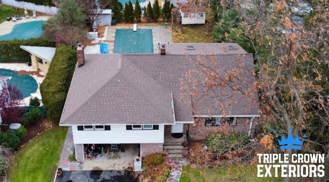 Aerial view of a residential home with autumn foliage and a pool area nearby.