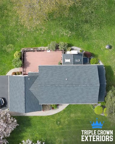 Aerial view of a well-maintained home with a landscaped yard and wooden deck. Triple Crown Exteriors.