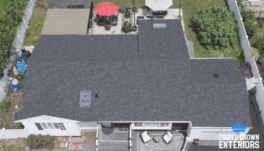 Aerial view of a modern home with a new sleek black roof and outdoor patio furniture.