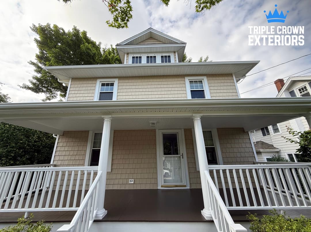 Front view of a charming three-story home with a porch and shingle siding. Triple Crown Exteriors logo.