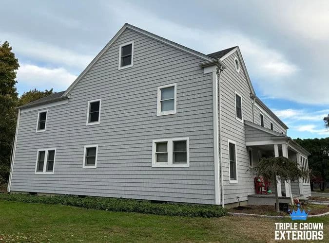 Modern gray home exterior with multiple windows and a covered porch, surrounded by greenery.