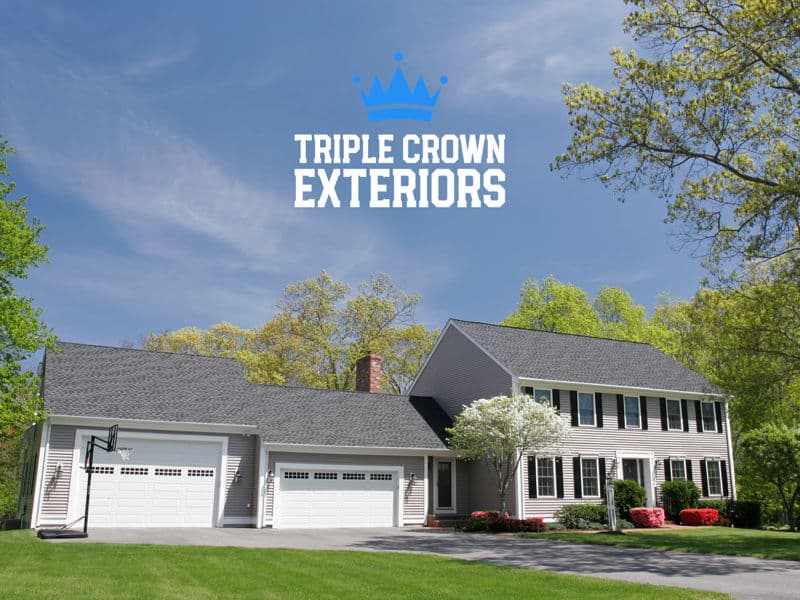 Modern suburban home with a large lawn, featuring Triple Crown Exteriors branding.