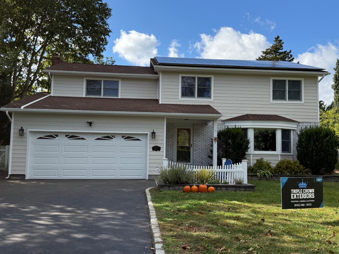 Modern home with solar panels, manicured lawn, and decorative pumpkins in front yard.