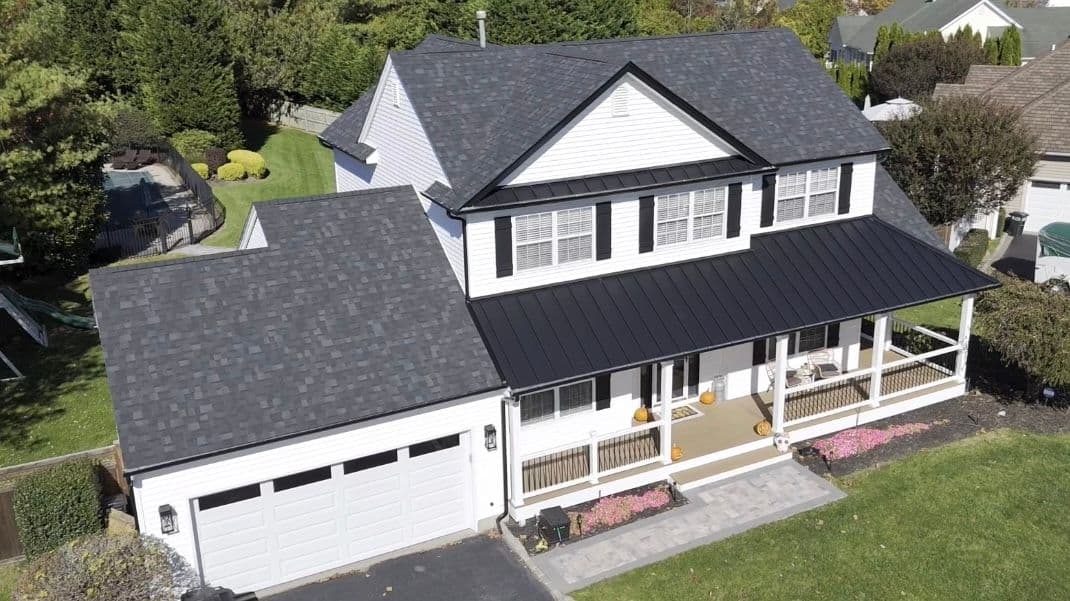 Aerial view of a modern white two-story house with gray roof and landscaped yard.
